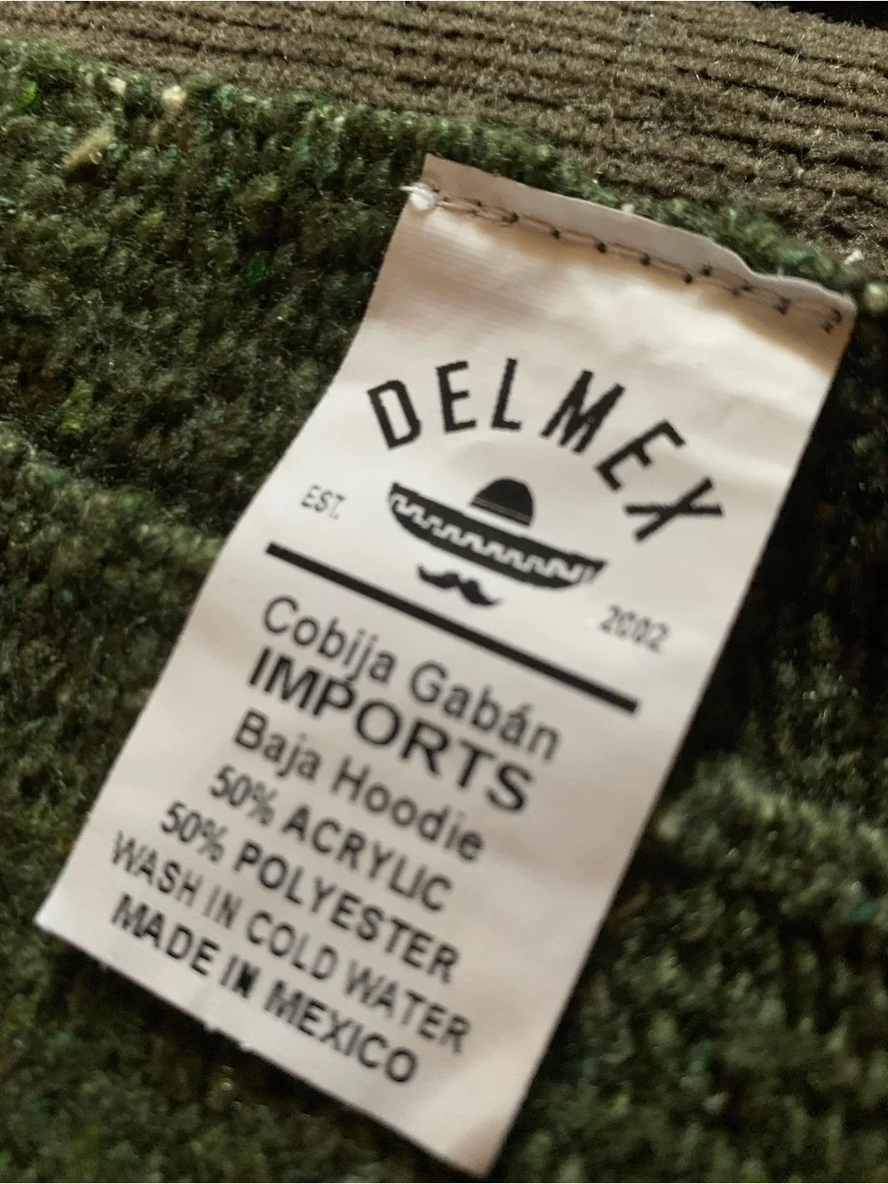 olive green Mexican-style blanket poncho featuring a geometric pattern